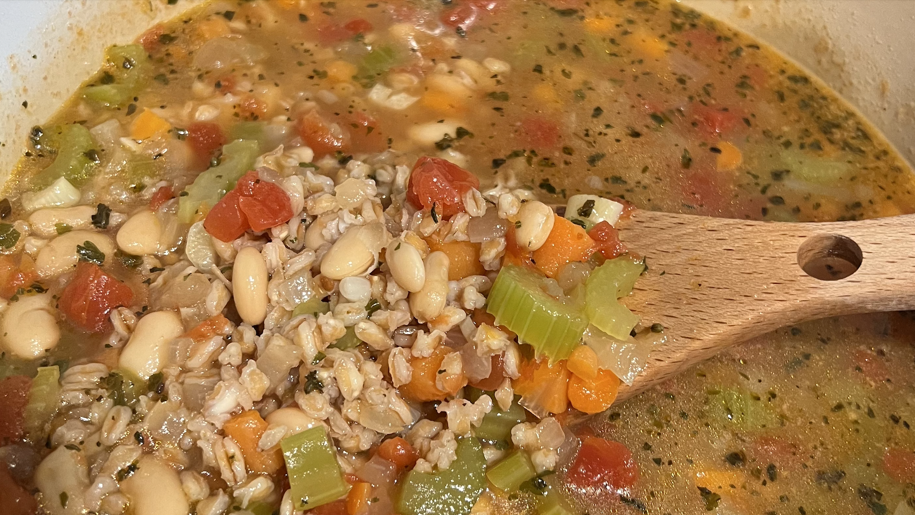 farro and white bean soup in pot with wooden spoon
